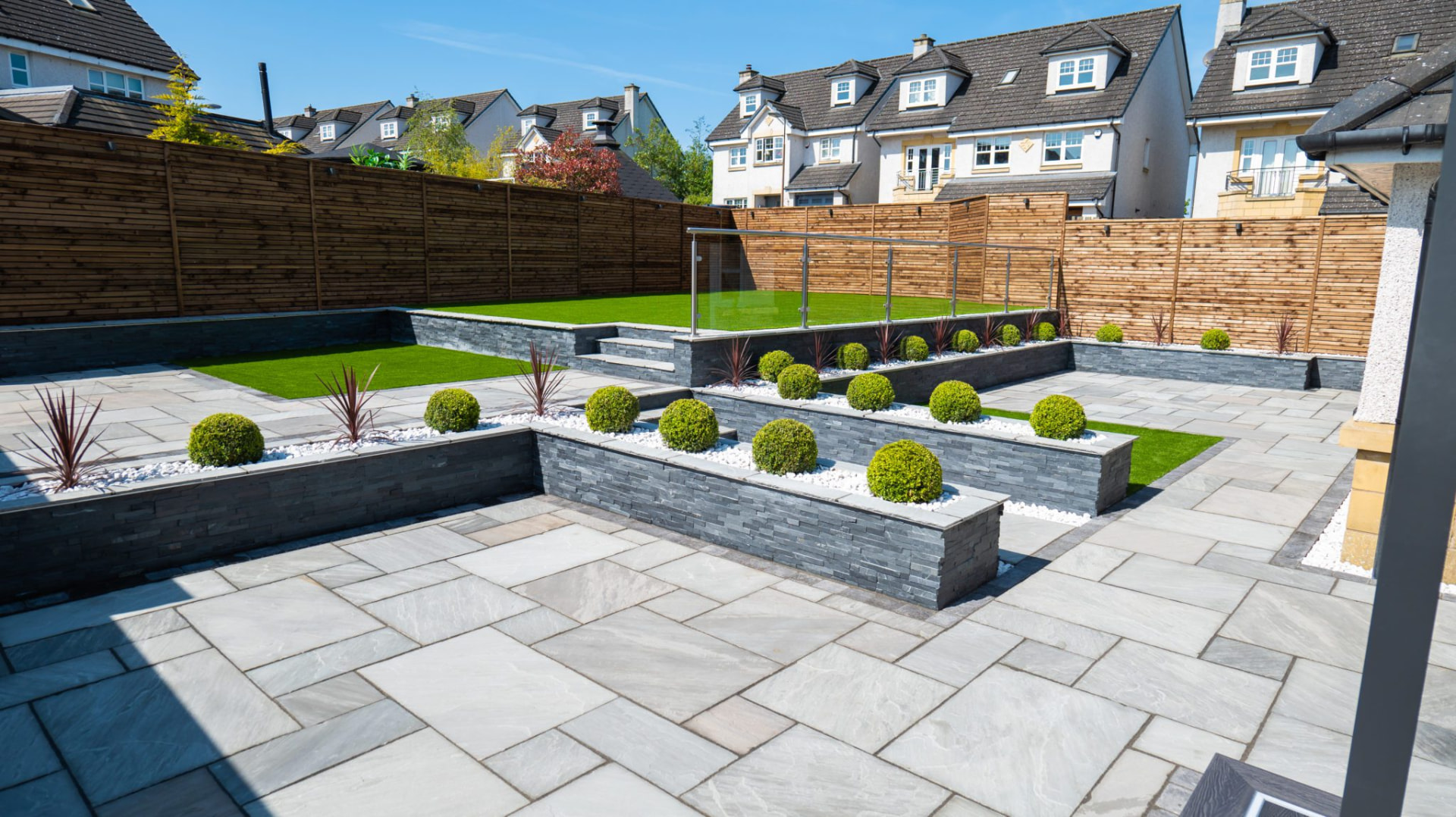 Completed Murray Landscapes garden with sandstone paving, slate tiered planters and lawn